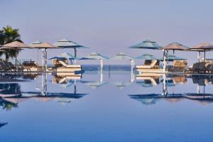 a swimming pool with chairs and umbrellas on the water at Atlantica Mare Village Paphos in Paphos City
