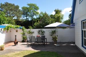 um pátio com uma mesa, cadeiras e um guarda-sol em Emmy's Cottage em Schoorl