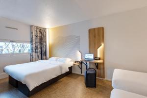 una camera d'albergo con un letto e un computer portatile su una scrivania di B&B HOTEL Ouistreham a Ouistreham