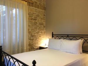 1 dormitorio con 1 cama con pared de piedra en Villa Antonis, en Lákka