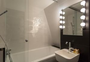 een badkamer met een douche, een wastafel en een spiegel bij Hôtel La Parizienne in Parijs