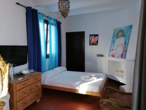 a bedroom with a bed with blue curtains and a dresser at El Beaterio in Tarifa