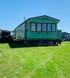 a green train car parked in a grass field at 157 Amour Caravan in Tywyn