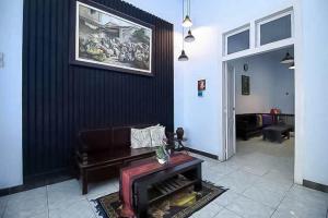 una sala de estar con sofá y una pintura en la pared en RedDoorz Near Stasiun Lawang, en Lawang