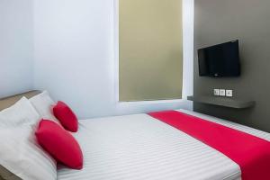 1 dormitorio con 1 cama con almohadas rojas y TV de pantalla plana en RedDoorz Near Stasiun Lawang, en Lawang