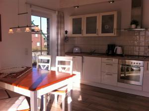 eine Küche mit weißen Schränken und einem Holztisch in der Unterkunft Haus Strandlaeufer in Dranske