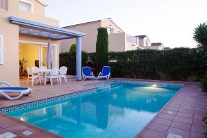 a swimming pool with chairs and a table and a house at Sagitario Villas in Son Carrio