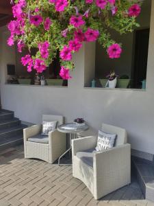 a patio with two chairs and a table with pink flowers at Apartments Sárika in Dlhá Ves