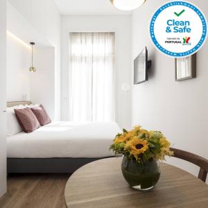 a room with a bed and a table with a vase of flowers at Lisbon Serviced Apartments - Chiado Emenda in Lisbon