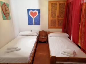 two beds in a room with a heart painting on the wall at El Beaterio in Tarifa