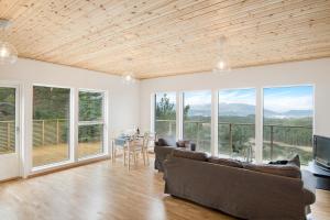 uma sala de estar com um sofá, uma mesa e janelas em House with fjord views Hommersåk ( stavanger, sandnes ) em Sandnes