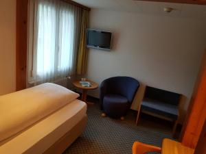 
a room with a bed, chair, desk and a television at Hotel Silberhorn in Lauterbrunnen
