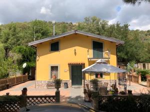 Casa amarilla con mesa y sombrilla en villa aurora, en Francavilla di Sicilia