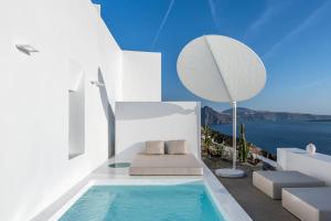 uma villa com uma piscina de mergulho e uma cadeira em The Saint Hotel em Oia