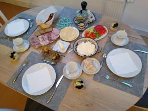 a table topped with white plates and bowls of food at Apartamenty Zielona Góra in Zielona Góra