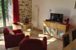 una sala de estar con TV de pantalla plana en un armario de madera en Ruby - Gîte 2 chambres dans vieux prieuré près de Carcassonne en Sainte-Eulalie