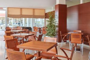 a restaurant with tables and chairs and a plant at Hotel Albatros Plava Laguna in Poreč