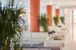 a row of white couches in a lobby with plants at Hotel Albatros Plava Laguna in Poreč