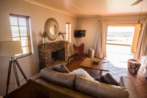a living room with a leather couch and a fireplace at Kwetu Guest Farm in Swellendam