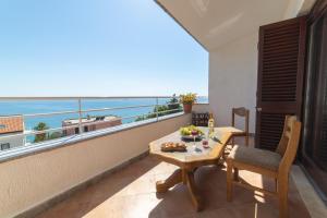 uma varanda com uma mesa e vista para o oceano em Apartments Sunrise em Split