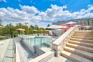 a resort with a pool and stairs and umbrellas at Hotel Mediteran Plava Laguna in Poreč