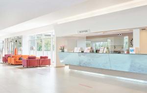 a lobby with orange chairs and a blue counter at Hotel Mediteran Plava Laguna in Poreč