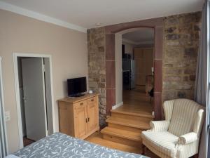 - une chambre avec un lit, une télévision et une chaise dans l'établissement Apartment am Schloss, à Sarrebruck