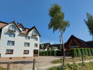 a white house with a tree in front of a building at Pensiunea La Mogan in Moieciu de Jos