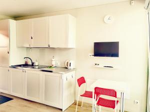 een keuken met witte kasten en rode stoelen bij Rise and Shine apartment in Juodkrantė