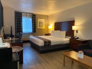 a hotel room with a large bed and a couch at Travelodge Inn & Suites by Wyndham Albany in Albany