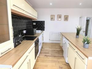 een keuken met witte kasten en houten aanrechtbladen bij Westbourne Villas in Bristol