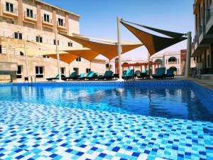 einen Pool mit Stühlen und Sonnenschirmen in einem Gebäude in der Unterkunft Levatio Suites Muscat, a member of Radisson Individuals in Muscat
