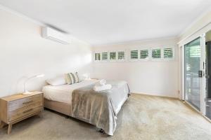a white bedroom with a bed and a window at Cabana @ Cupania in Mudjimba
