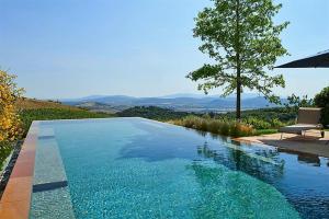 a swimming pool with a table and a chair and a tree at Sequerciani in Tatti