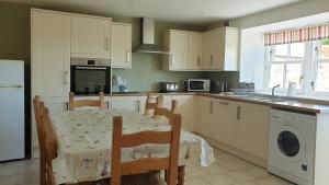 a kitchen with a table and chairs and a kitchen with white cabinets at Old Farm Holiday Cottages - Scottish Borders in Chirnside