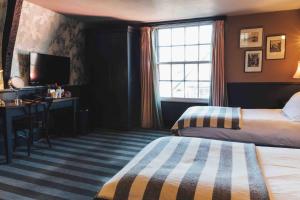 a hotel room with two beds and a desk and a window at The Crown And Thistle in Abingdon
