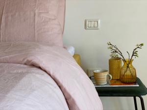 a bed with a pink comforter and a side table with a cup at Allegro Holiday in Nizza Monferrato