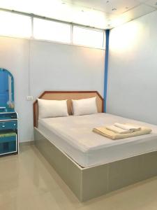 a bedroom with a bed with white sheets and windows at Tanarod Gueshouse in Surat Thani