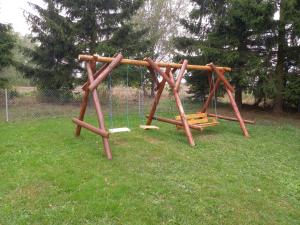 a wooden swing set in a field of grass at Agroturystyka pod świerkami in Ryn