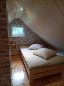 a bed in a room with a wooden ceiling at Agroturystyka pod świerkami in Ryn