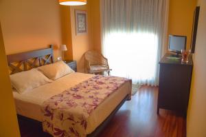 1 dormitorio con 1 cama, TV y ventana en Apartamento en Beiramar, en O Grove