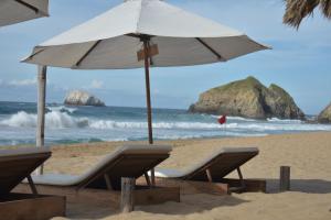 a beach area with chairs and umbrellas at Posada Mexico in Zipolite