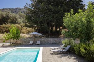 a swimming pool with two lounge chairs and an umbrella at Tessera Villa, a Serene Escape in Nature with Pool, By ThinkVilla in Spílion