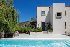 a villa with a swimming pool in front of a house at Tessera Villa, a Serene Escape in Nature with Pool, By ThinkVilla in Spílion