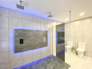 a bathroom with a toilet and a wall with blue lights at Fabrik Apartments - Harrowside by Blackpool Service Apartements in Blackpool +75 photos