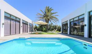 a swimming pool in front of a house at OCEAN BREEZE SUNSET BEACH - Boutique Guesthouse - Cape Town in Cape Town