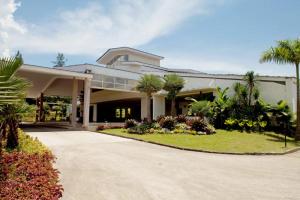 a large white building with palm trees and a driveway at Taman Bukit Palem Resort in Bogor