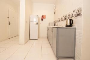 a white kitchen with a refrigerator and a tile floor at مكارم الورود للشقق المخدومة in Taif