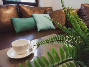 a coffee cup sitting on top of a couch next to a plant at Apartamenty Dworcowa 45 in Gliwice