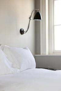 Una cama con almohadas blancas y una lámpara junto a una ventana. en Kings Arms Hotel, en Berkhamsted